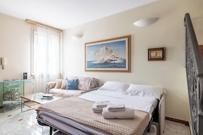 A hotel room with a bed, a sofa, a glass table with a vase, and a painting on the wall. - VILLA CATERINA A FEW STEPS FROM THE SEA: PET FRIENDLY, BBQ, TERRACE & RELAX (San Bartolomeo al Mare)