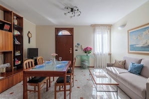 A dining area with a table, chairs, a television, a bookshelf, and a painting on the wall. - VILLA CATERINA A FEW STEPS FROM THE SEA: PET FRIENDLY, BBQ, TERRACE & RELAX (San Bartolomeo al Mare)