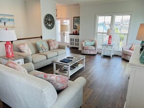 Ein Wohnzimmer mit Sofa, Sesseln, Couchtisch und einer Wanduhr.
