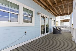 Eine überdachte Veranda mit Holzbalken, Geländer und Gartenmöbeln.