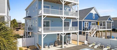 A multi-story building with a pool, outdoor seating, and a covered deck area.