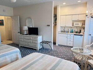 A hotel room with a bed, a dresser, a television, a small table, and a kitchenette. - Golden Memories / 91 Genoes Point Rd 2 Bedroom Home (Supply)