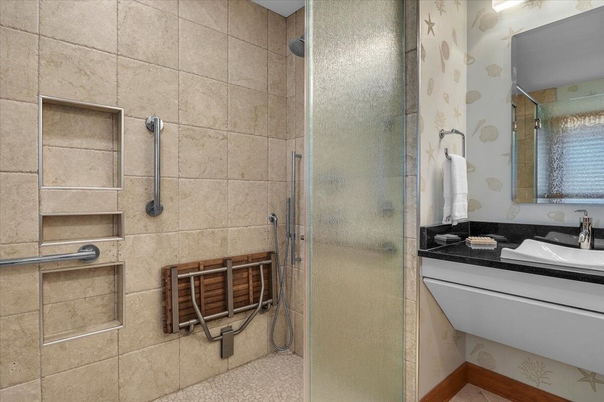 A bathroom with a shower, a sink, and a mirror.