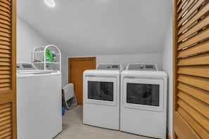 A laundry room with three stacked washers and dryers, a drying rack, and a shelf with cleaning supplies. - Sea You Reel Soon / 1207 Ocean Blvd. West 6 Bedroom Home (Supply)