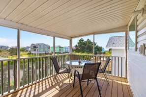 Eine überdachte Terrasse mit Tisch und Stühlen, mit Blick auf eine Wohngegend.