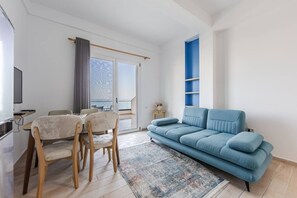 Een moderne woonkamer met een bank, stoelen, een televisie en een balkon met uitzicht.