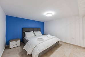 Een slaapkamer met een bed, nachtkastje en nachttafel.