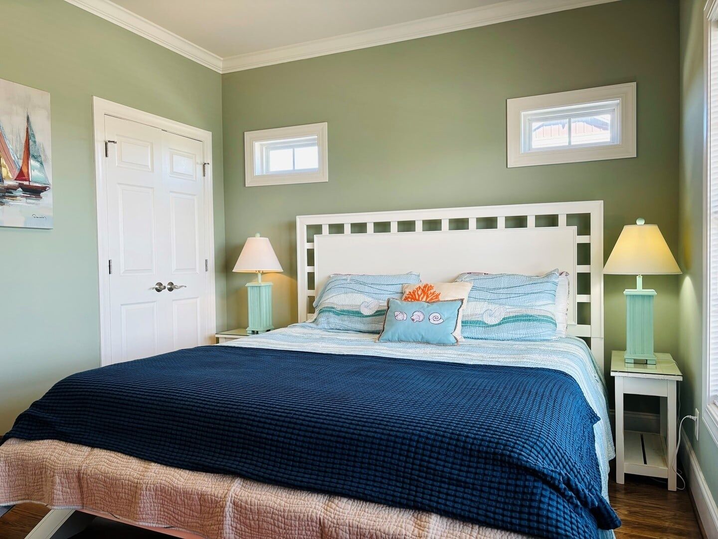 A bedroom with a bed, two bedside tables, a door, and a window.