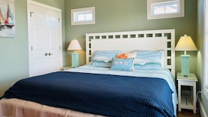 Quarto com uma cama, duas mesas de cabeceira, uma porta e uma janela.