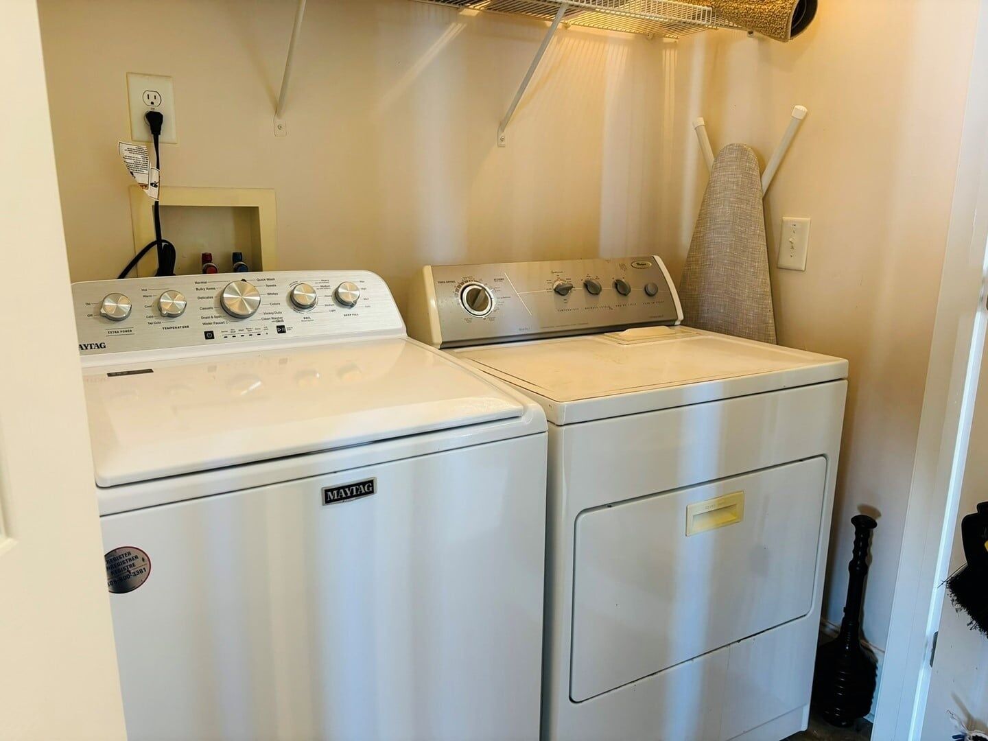 Une buanderie équipée de deux machines à laver et deux sèche-linge Maytag, d’une prise de courant et d’un étendoir.