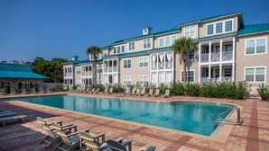 A pool area with lounge chairs, a swimming pool, and a building with balconies. - 30a Getaway 3 Bedroom Condo (Santa Rosa Beach)