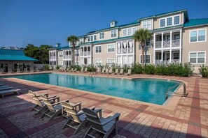 A pool area with lounge chairs, a swimming pool, and a building with balconies. - 30a Getaway 3 Bedroom Condo (Santa Rosa Beach)