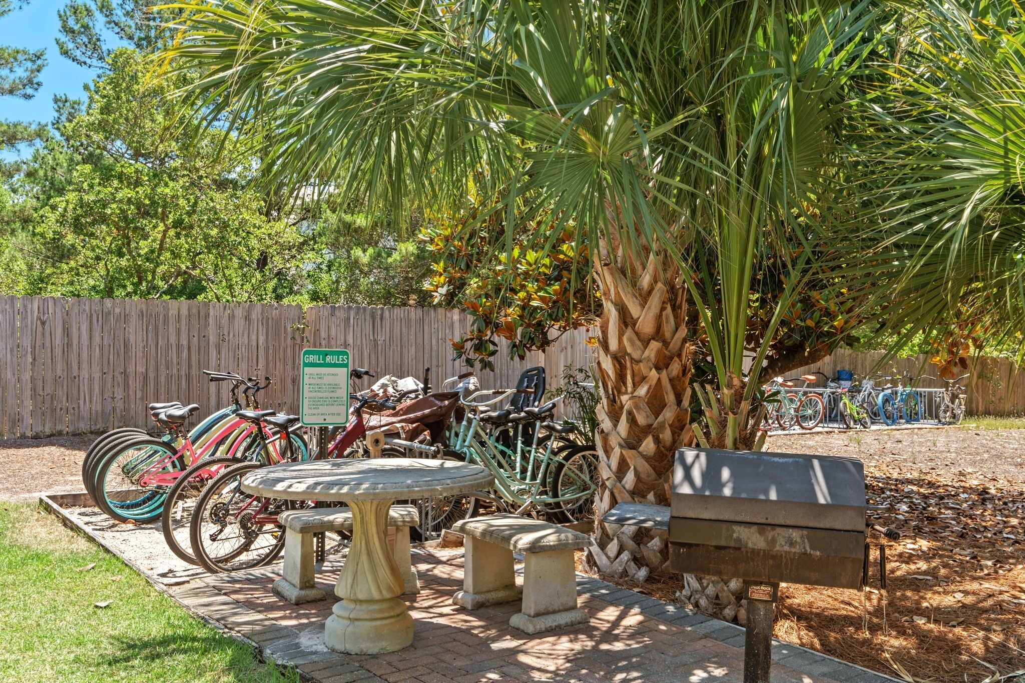 A patio area with a table and benches, surrounded by a wooden fence and various bicycles.
