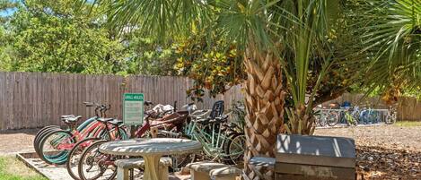 A patio area with a table and benches, surrounded by a wooden fence and various bicycles.