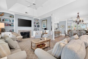 A spacious living room with a fireplace, a television, and a chandelier.