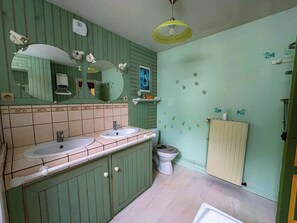 Un bagno con due lavandini, un water, uno specchio e un termosifone.