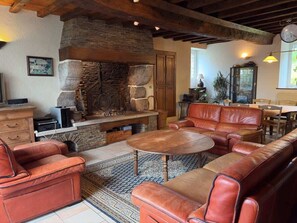 Un salon chaleureux avec une cheminée en pierre, des canapés en cuir et un coin repas.