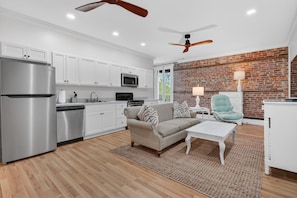 A modern kitchen with white cabinets, stainless steel appliances, and a brick accent wall. - River Room Getaway On Front Street - Suite C 1 Bedroom Apts (Georgetown)