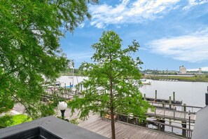 A waterfront view with a dock, a boat, and a building in the background. - River Room Getaway On Front Street - Suite C 1 Bedroom Apts (Georgetown)