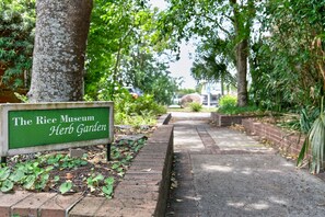 A pathway leading to The Rice Museum Herb Garden with a signboard. - River Room Getaway On Front Street - Suite C 1 Bedroom Apts (Georgetown)