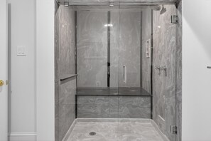 A modern bathroom with a glass-enclosed shower, a marble-topped sink, and a visible toilet. - River Room Getaway On Front Street - Suite C 1 Bedroom Apts (Georgetown)