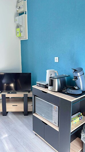 Une petite cuisine équipée d’un grille-pain, d’une machine à café et d’une bouilloire, ainsi qu’une télévision et un four à micro-ondes.