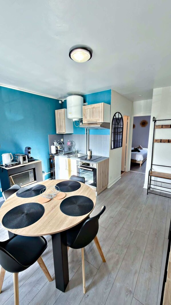 Une cuisine moderne avec une table de salle à manger ronde, des chaises noires et un four encastré.