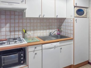 Uma cozinha com fogão a gás, forno, pia e lava-louças.