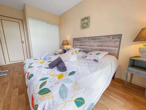 Quarto com cama, mesa de cabeceira, abajur, guarda-roupa e um quadro pendurado na parede.