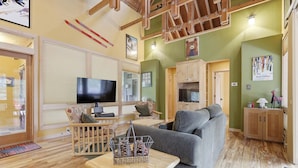 Ein gemütliches Wohnzimmer mit Fernseher, Holzmöbeln und einer Wanddekoration mit Bärenmotiv.