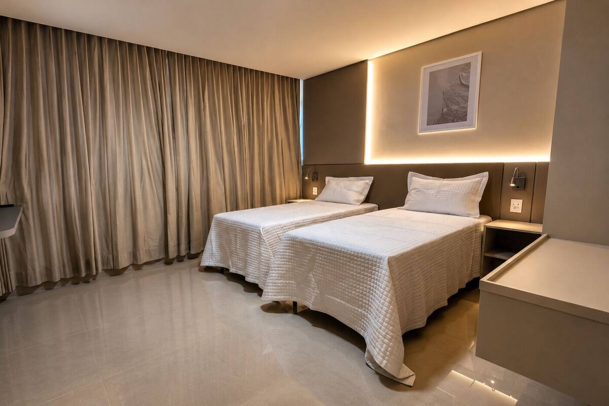 Une chambre d’hôtel avec deux lits, une télévision, une table de chevet et une commode, ainsi qu’un tableau accroché au mur.