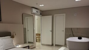 Une chambre d’hôtel moderne avec un grand lit, une salle de bain dotée d’une grande baignoire et un dressing.