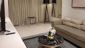 Un salon moderne avec un téléviseur à écran plat, un canapé, une table basse ornée d’un vase et deux lampadaires.