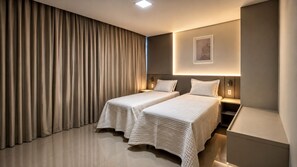 Een moderne hotelkamer met twee bedden, een groot raam met gordijnen, een wandlamp en een klein kunstwerk.