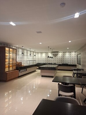 A modern kitchen with a central island, pendant lighting, and a dining area with chairs and tables.