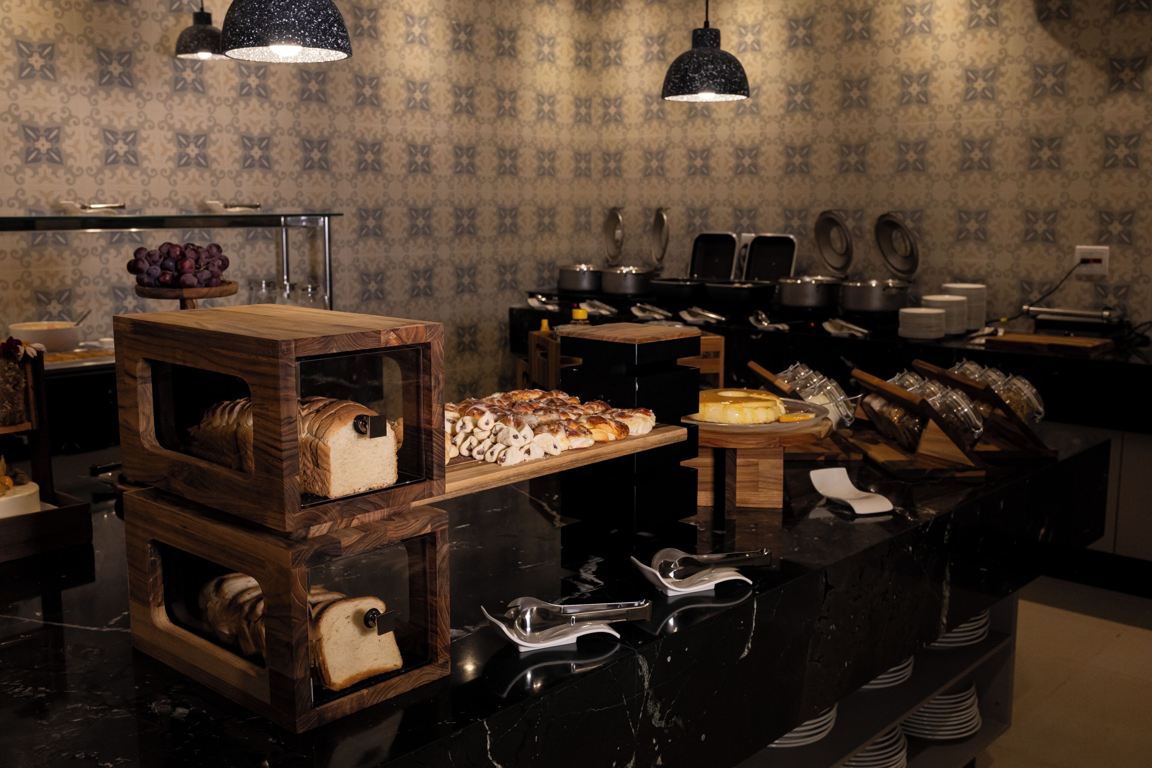 Un buffet est installé sur un comptoir noir, avec différents plats et ustensiles à disposition.