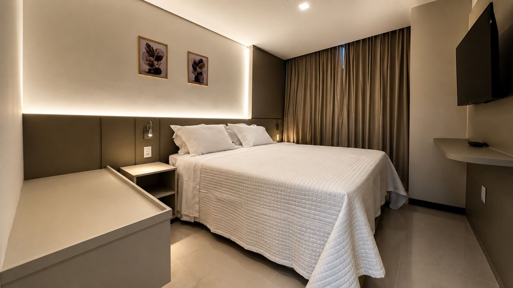 Een moderne hotelkamer met een groot bed, nachtkastjes, een flatscreen televisie en kunst aan de muur.
