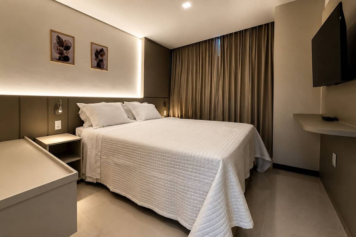 Une chambre d’hôtel moderne, dotée d’un grand lit, de tables de chevet, d’un téléviseur à écran plat et d’œuvres d’art accrochées au mur.