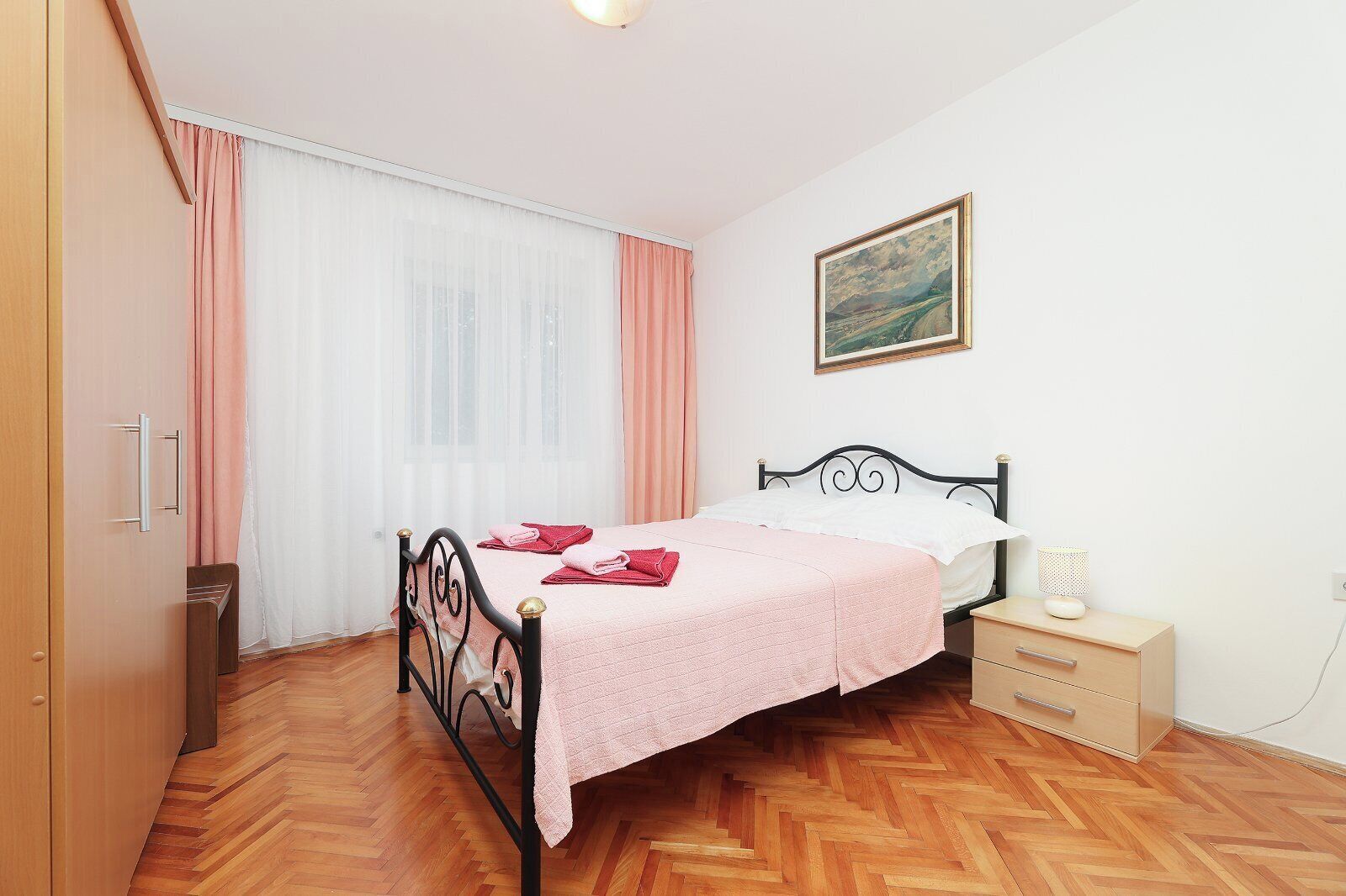 Ein Schlafzimmer mit einem Bett, einem Nachttisch, einer Lampe, einem Gemälde und einem Kleiderschrank.