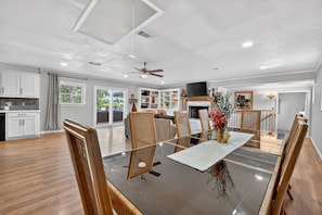 A spacious dining area with a large table, chairs, a ceiling fan, and a fireplace. - Lakefront with Treehouse, Pool, Gameroom and hottub. 5BR, 4bath (Azle)