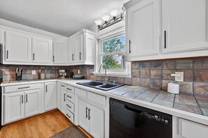 A kitchen with white cabinets, a double sink, and a dishwasher. - Lakefront with Treehouse, Pool, Gameroom and hottub. 5BR, 4bath (Azle)