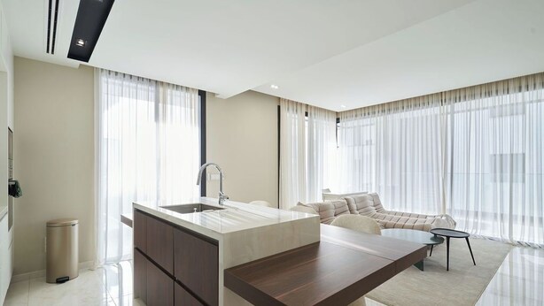 A modern kitchen with a central island, a built-in sink, and a dining area with a sofa and a small table. - La Maison 2BR Luxury Apartment Nicosia (Egkomi Lefkosias)