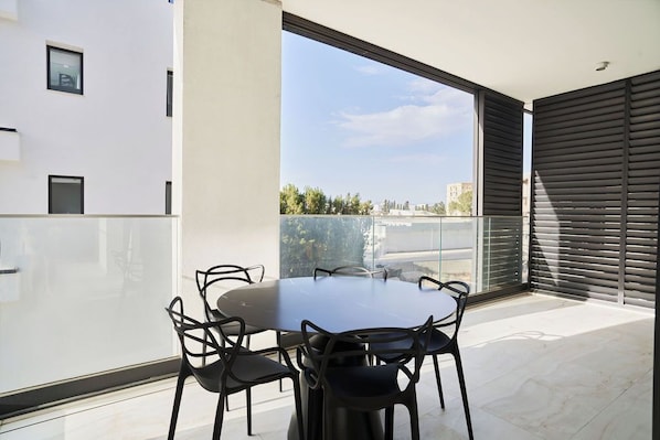 Un espace repas moderne avec une table ronde et des chaises, de grandes fenĂȘtres et une vue sur la ville.