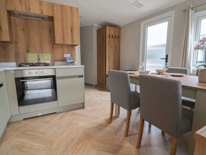 Eine moderne Küche mit Holzausstattung, einem eingebauten Ofen und einer Essecke mit grauen Stühlen.