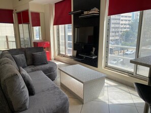 Een woonkamer met een bank, een salontafel, een televisie en een open haard.
