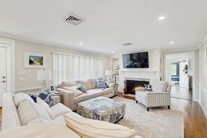 A living room with a fireplace, a sofa set, a television, and a dining area. - Mid-Cape Retreat, Near Beaches & Nice Yard (Yarmouth)