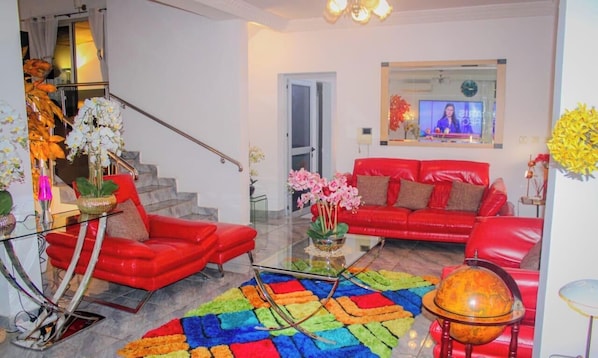 A modern living room with a red sofa, a glass coffee table, and a colorful rug.