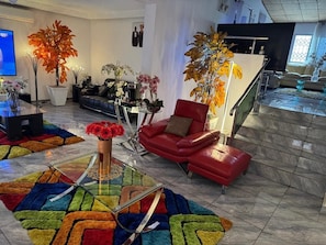 A modern living room with a red leather sofa, a glass coffee table, and a colorful rug.