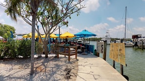 Ein Restaurant am Wasser mit Außenbereich, Sonnenschirmen und einer Anlegestelle für Boote.