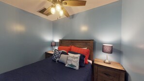 Ein Schlafzimmer mit einem Bett, zwei Nachttischen, einem Deckenventilator und zwei Wandleuchten.